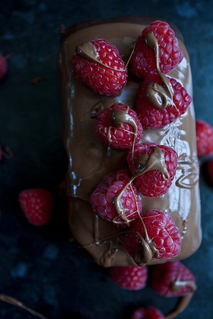 A chocolate cake topped with milk chocolate and raspberries