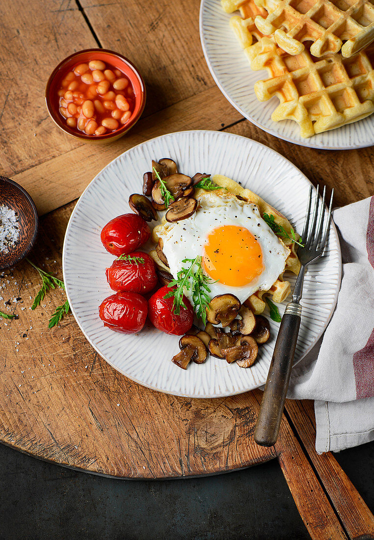 Hearty waffles with a fried egg, tomatoes, mushrooms and baked beans