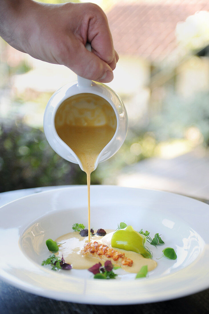 Sauce (soup) being poured onto a plate