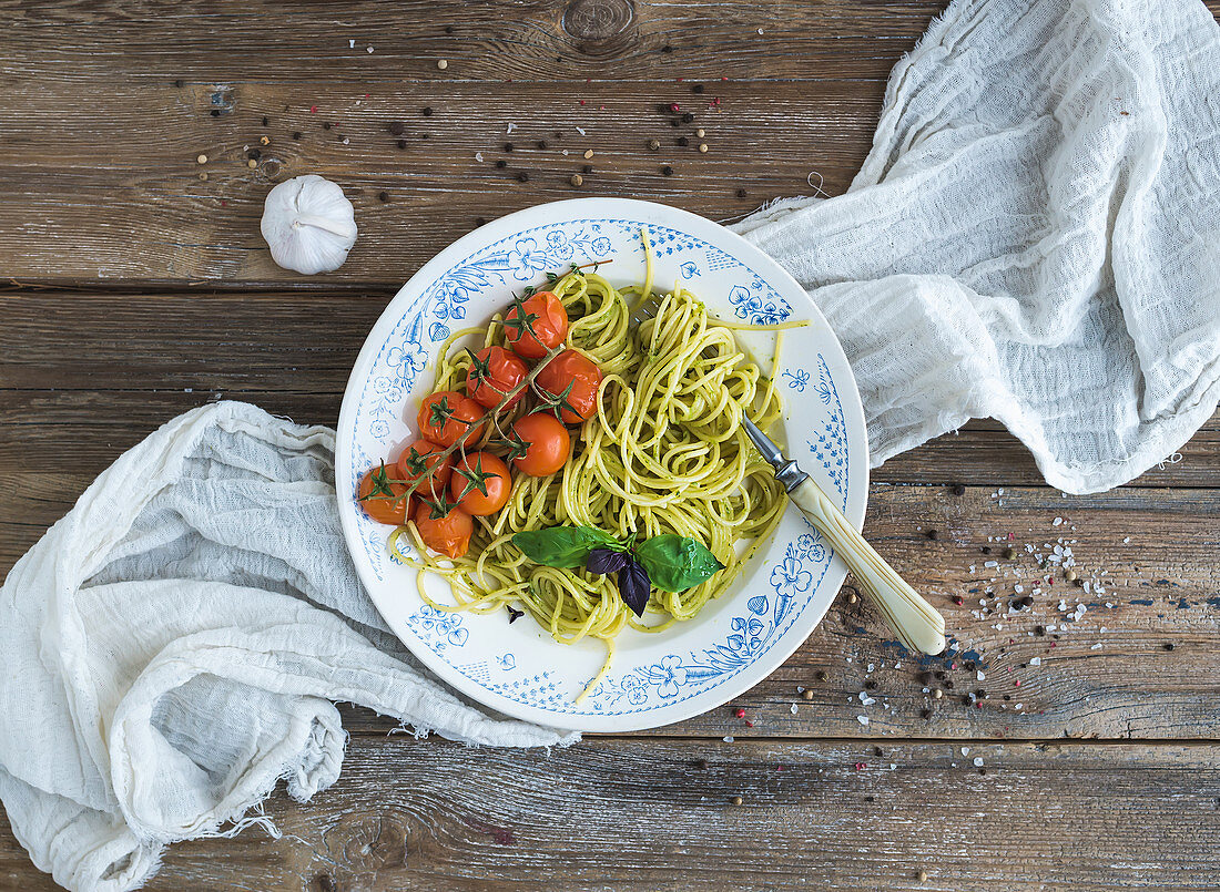 Pasta spaghetti with pesto sauce, basil, garlic and baked cherry-tomatoes