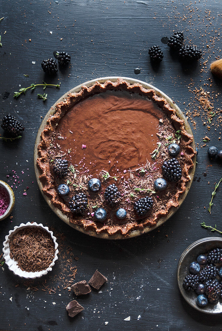 Chocolate tart topped with blackberries and blueberries on a vintage pie plate