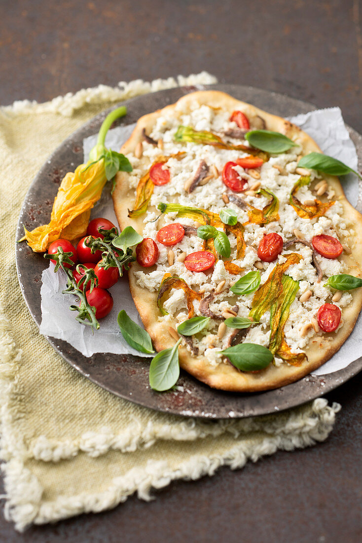 Pizza mit Ricotta, Zucchiniblüten, Pinienkernen, Anchovis und Kirschtomaten