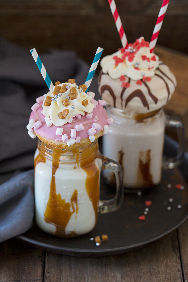 Two caramel freakshakes decorated with doughnuts