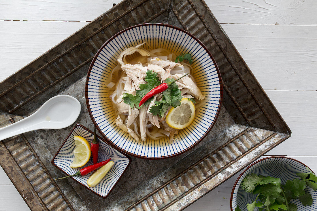 Pho Ga (chicken soup with rice noodles, Vietnam) on a tray