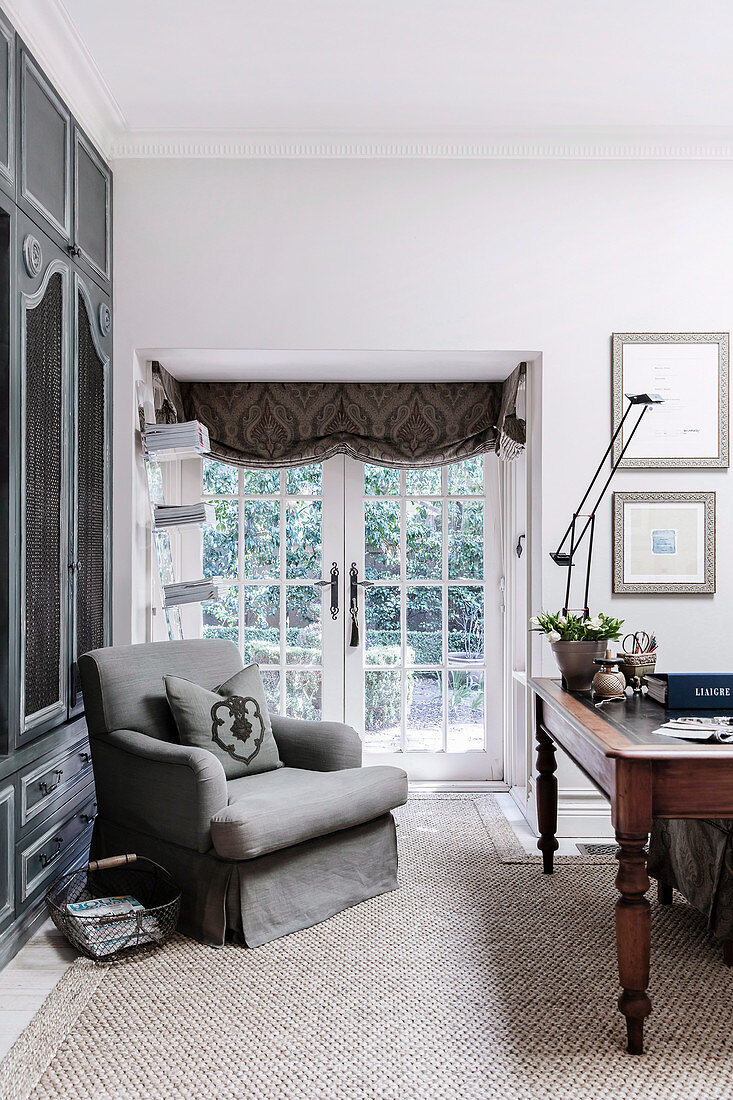 Gray upholstered armchair and antique desk in the study