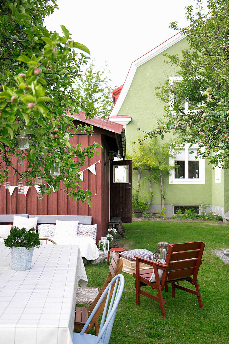 Sitzplatz im skandinavischen Sommergarten vorm grünen Haus