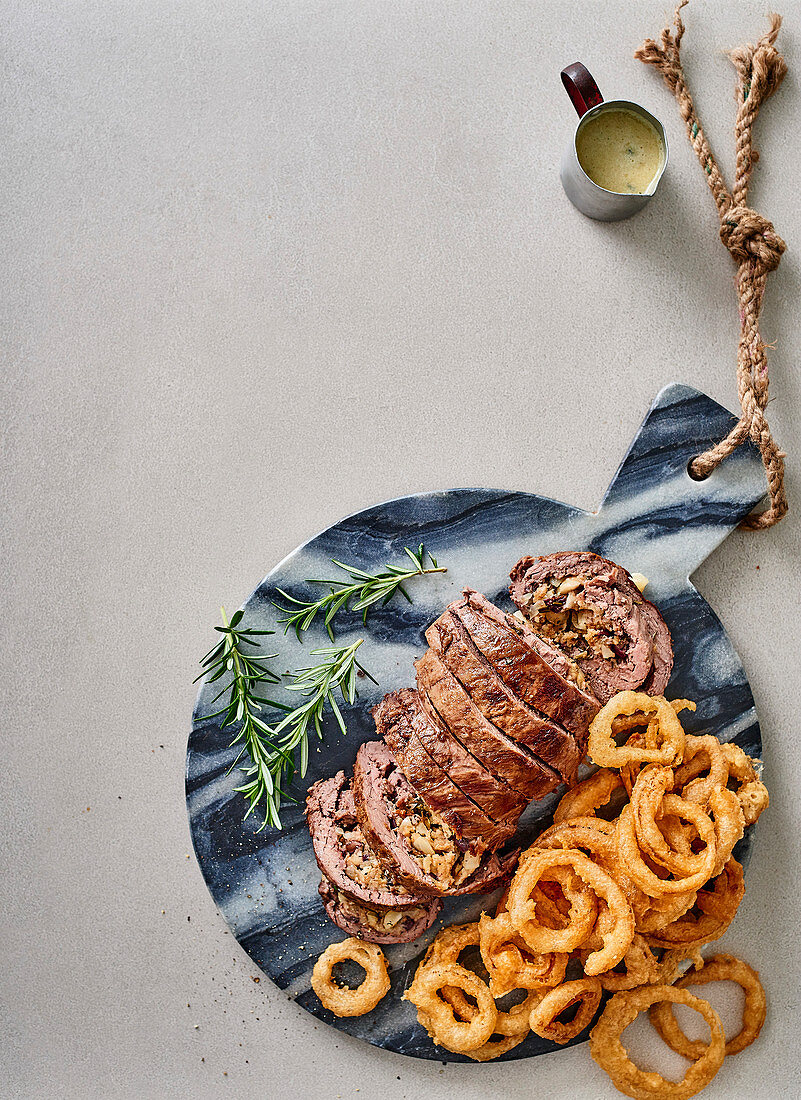 Rosemary-stuffed beef fillet with blue cheese sauce and onion rings