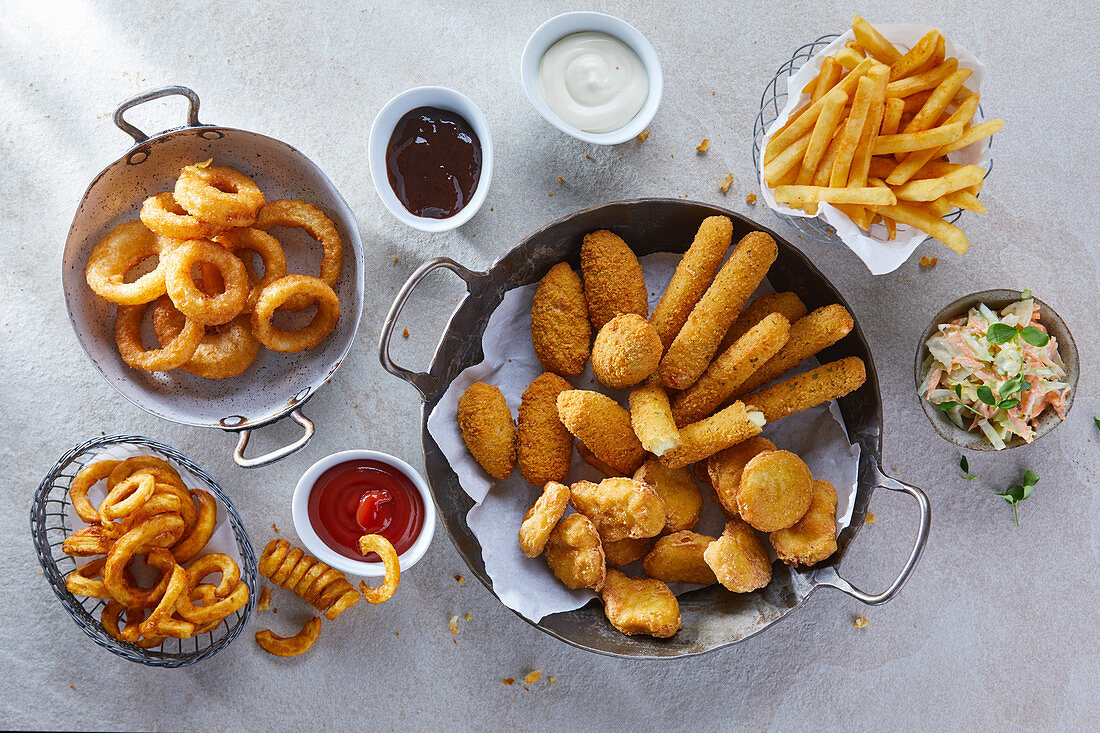 Various fast food snacks with dips, chips and coleslaw