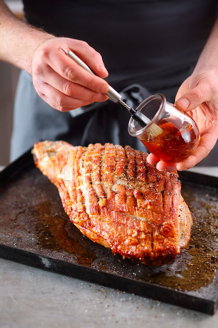 Young roast pork being brushed with honey