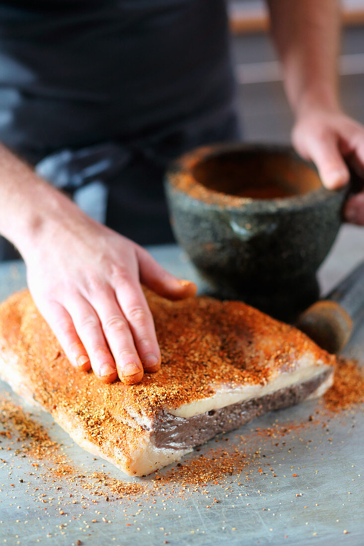 Wet-cured beef brisket being seasoned with a rub