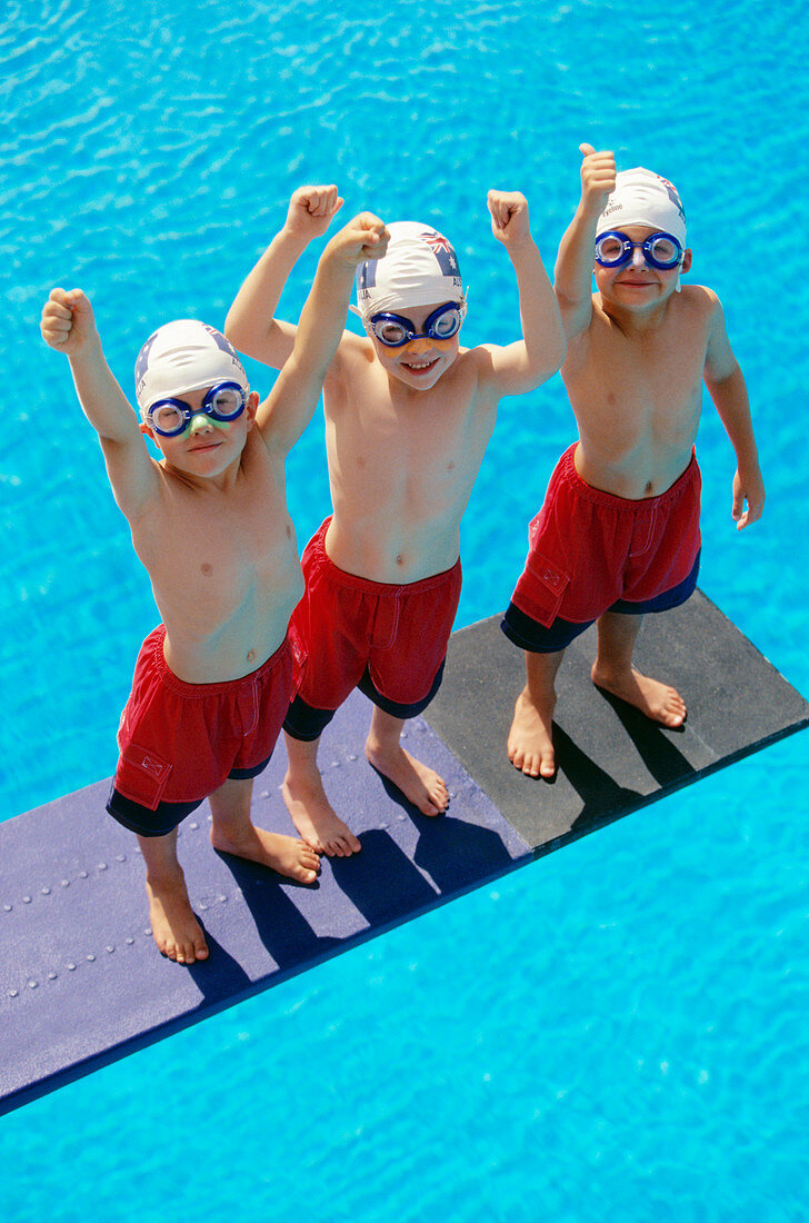 Three boys standing on a diving board