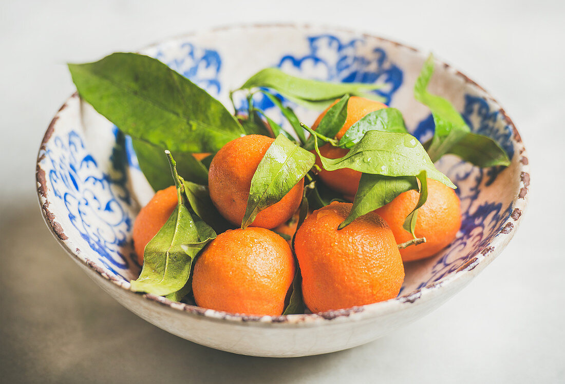 Mandarinen mit Blättern in Keramikschale