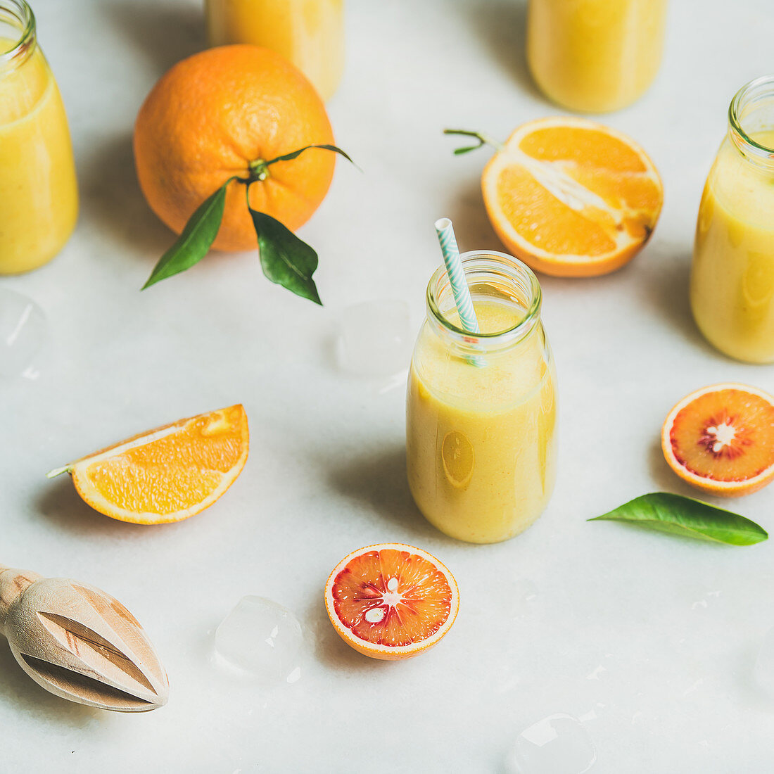 Healthy yellow smoothie with citrus fruit, ginger, ice in glass bottles
