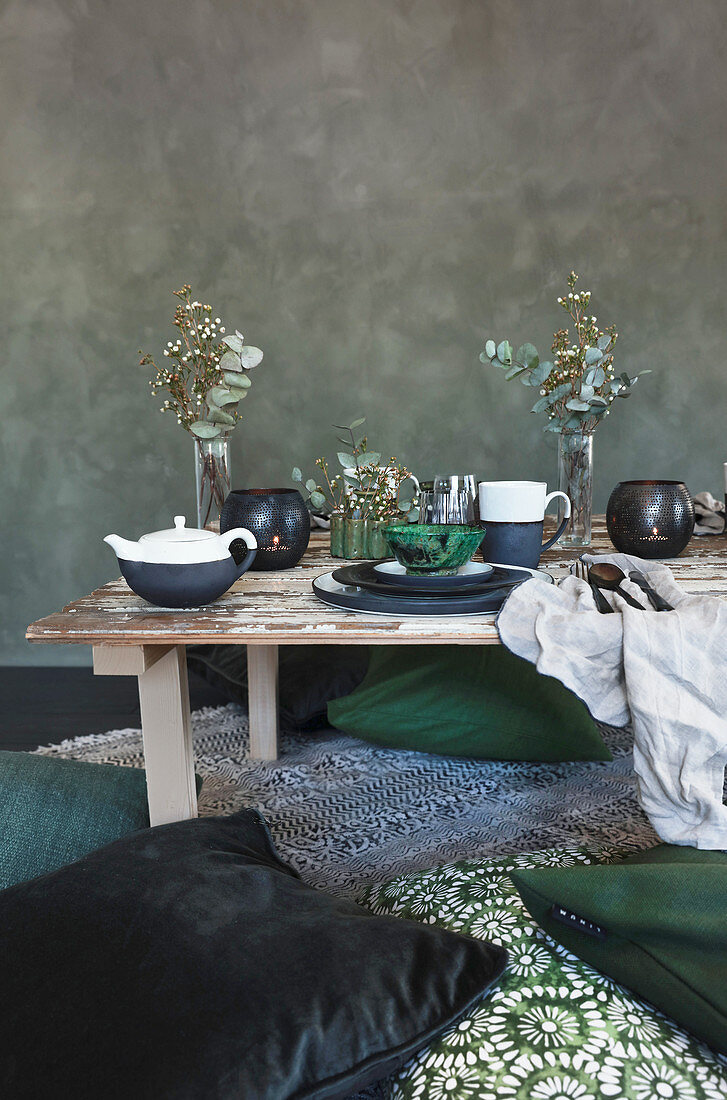 Green cushions on floor around low table with place settings