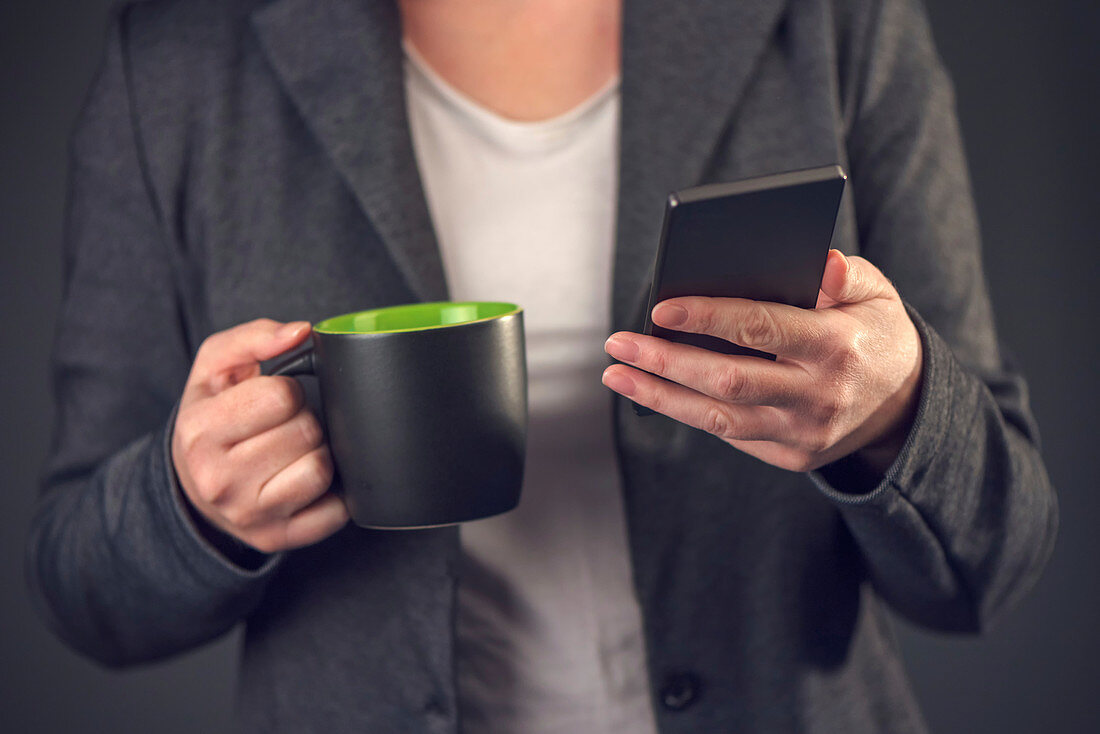 Woman with mug and smartphone
