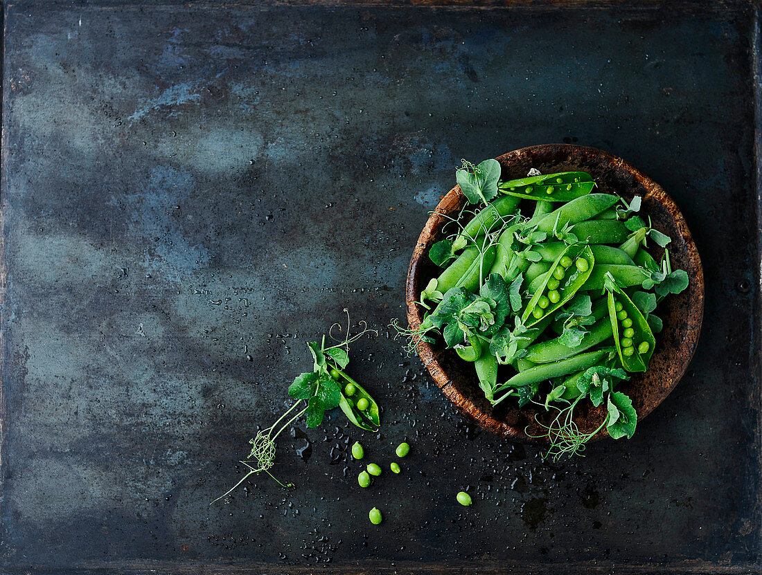 Fresh pea pods in a wooden bowl