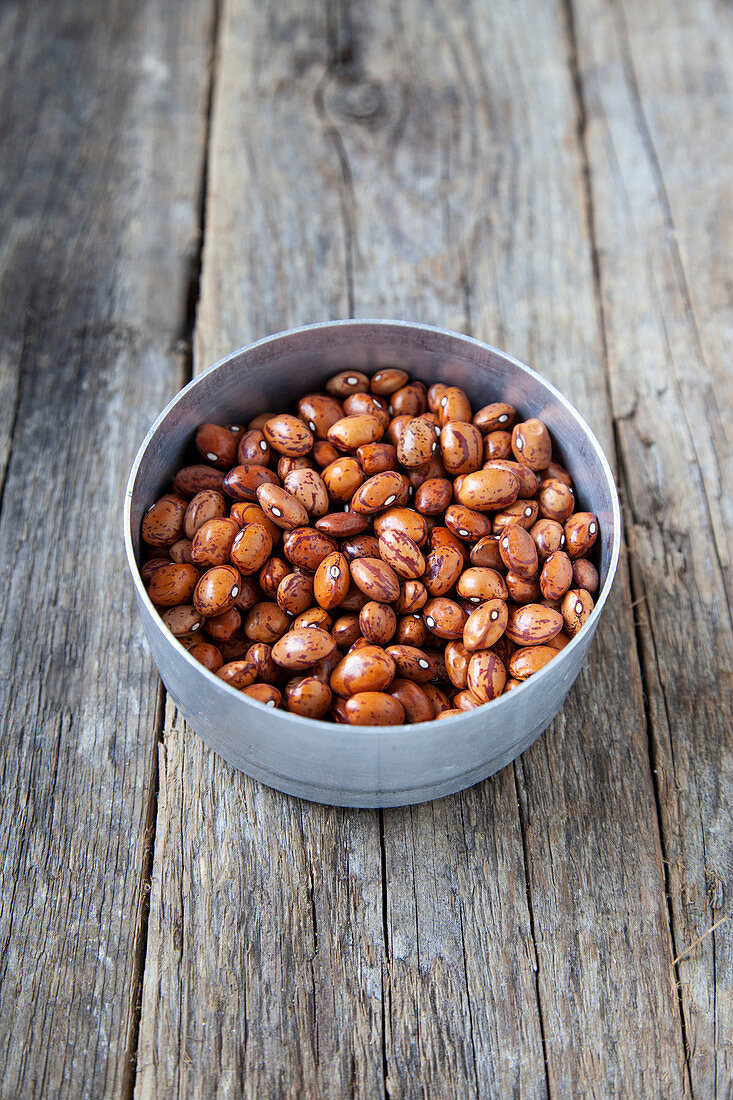 Dried quail beans in a small bowl on a wooden background