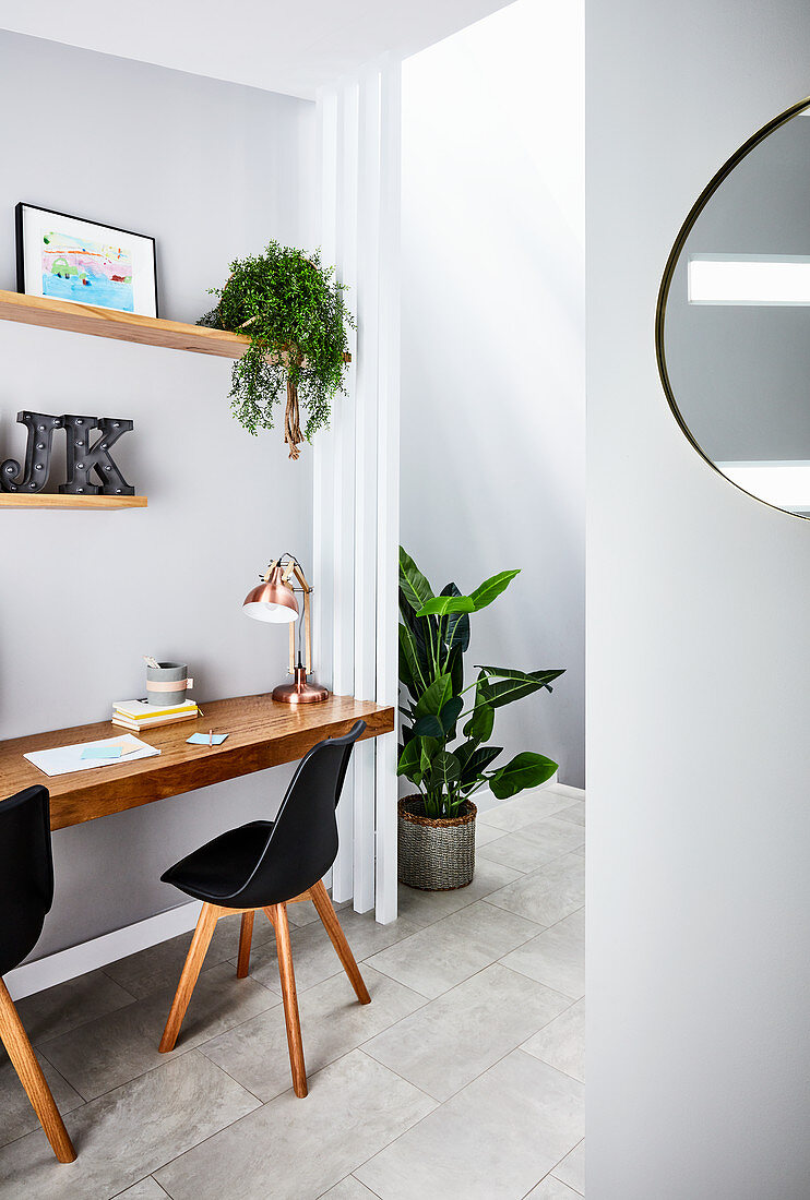 Potted plant in open doorway next to floating desk with black chairs