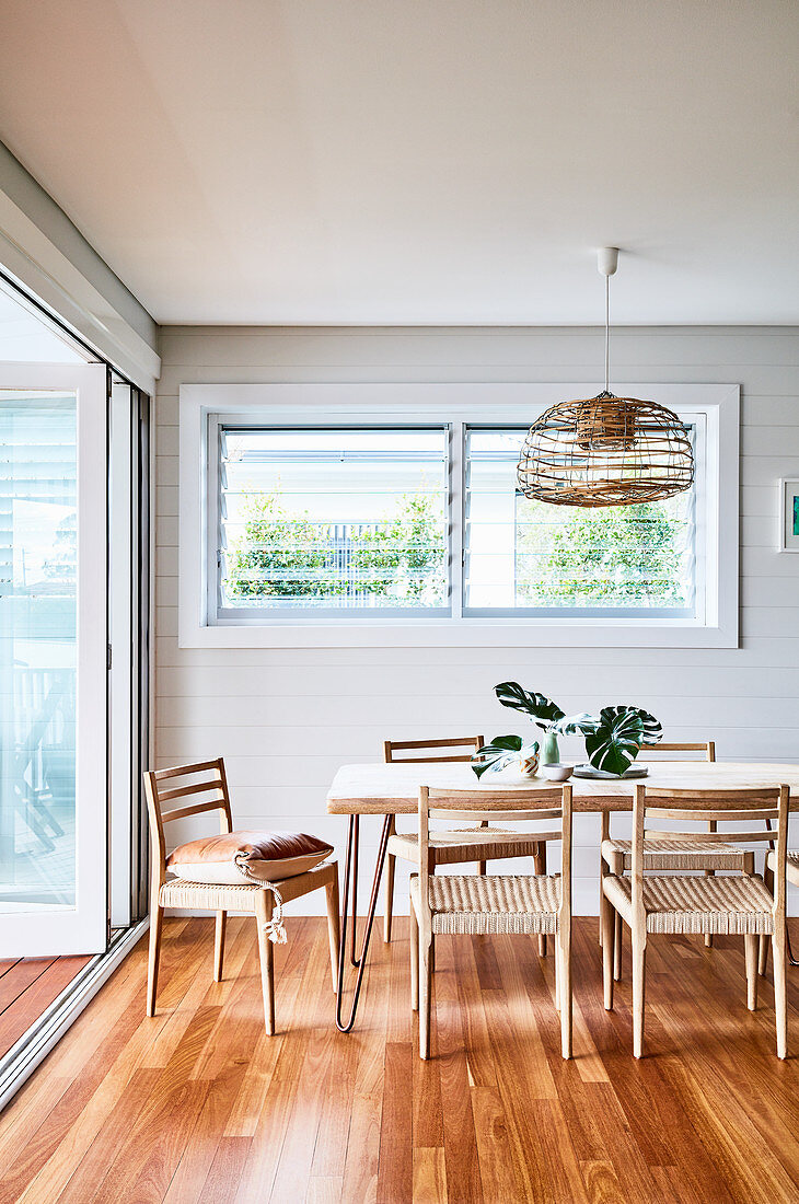 Dining table and chairs on parquet floor next to open terrace doors