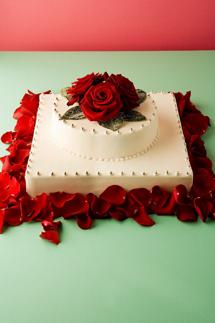 A wedding cake decorated with silver pearls and rose petals