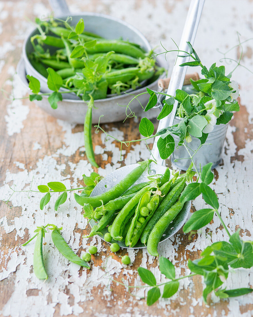 an arrangement of peas with flowers and a draining spoon
