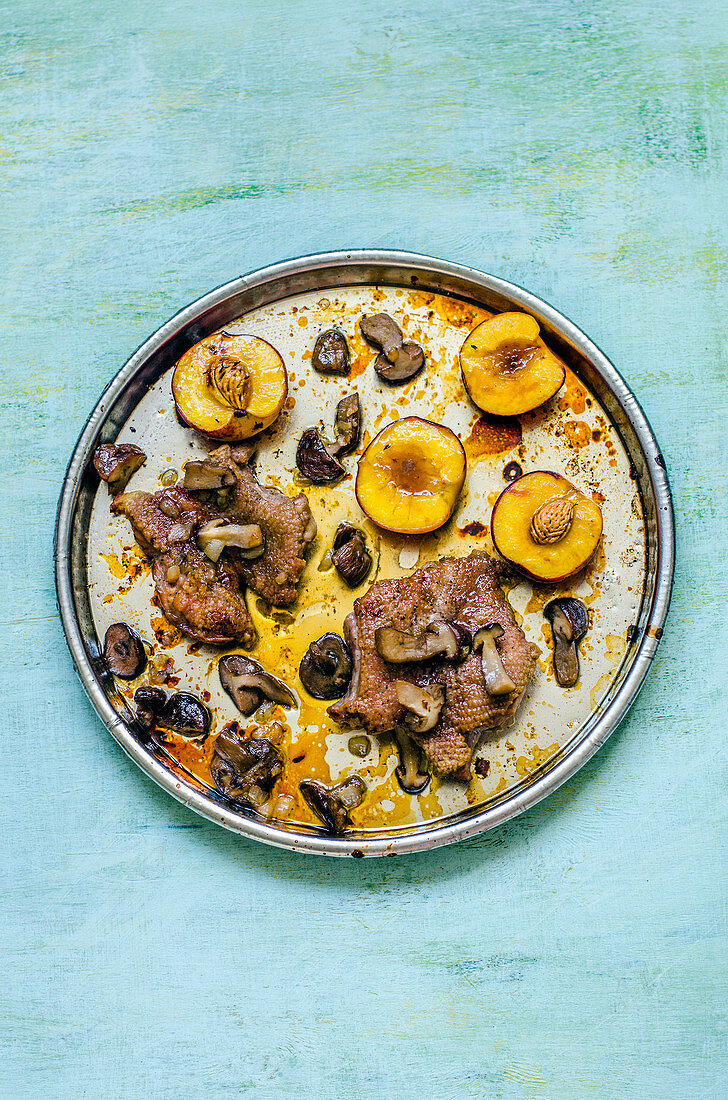 Duck breast with caramelized peaches and mushrooms on a round tray