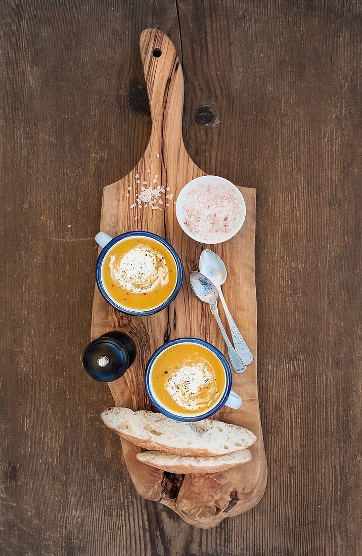 Selbstgemachte Kürbiscremesuppe mit Kräutern und Weissbrotscheiben