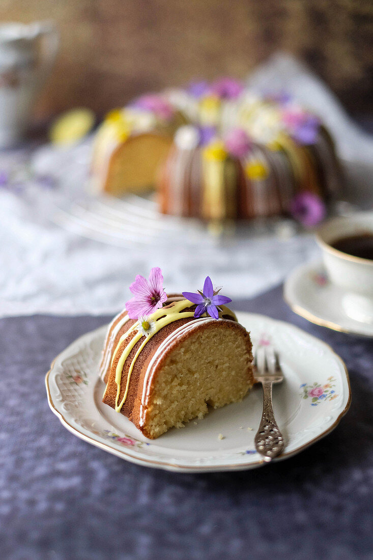 A guglhupf with yellow and white icing and edible flowers