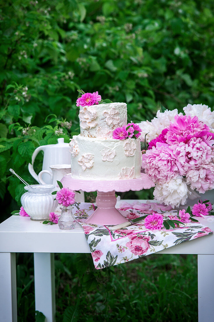 Buttercream cake with peonies in a garden