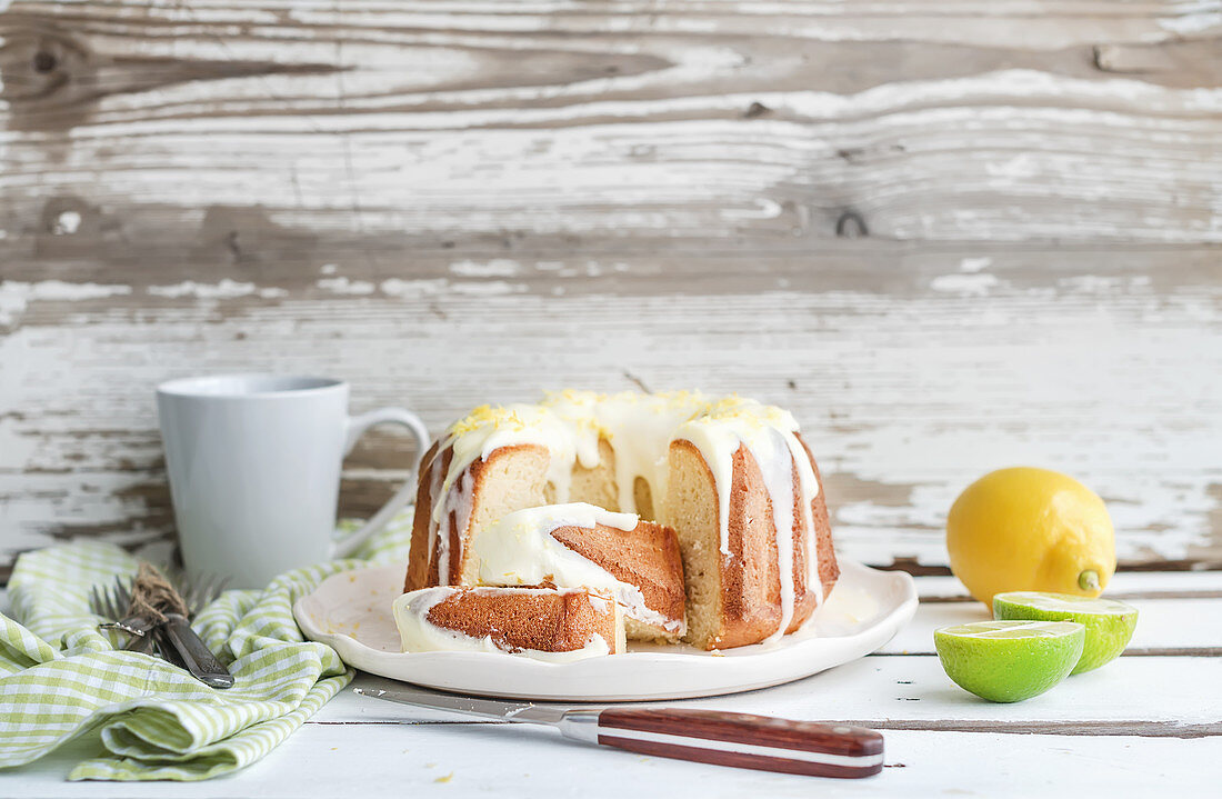 Moist lime and lemon bundt yoghurt cake, white rustic wooden background
