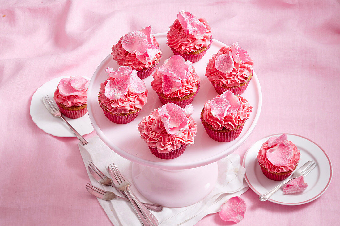 Cupcakes mit rosa Schokoladencremefrosting und Rosenblättern