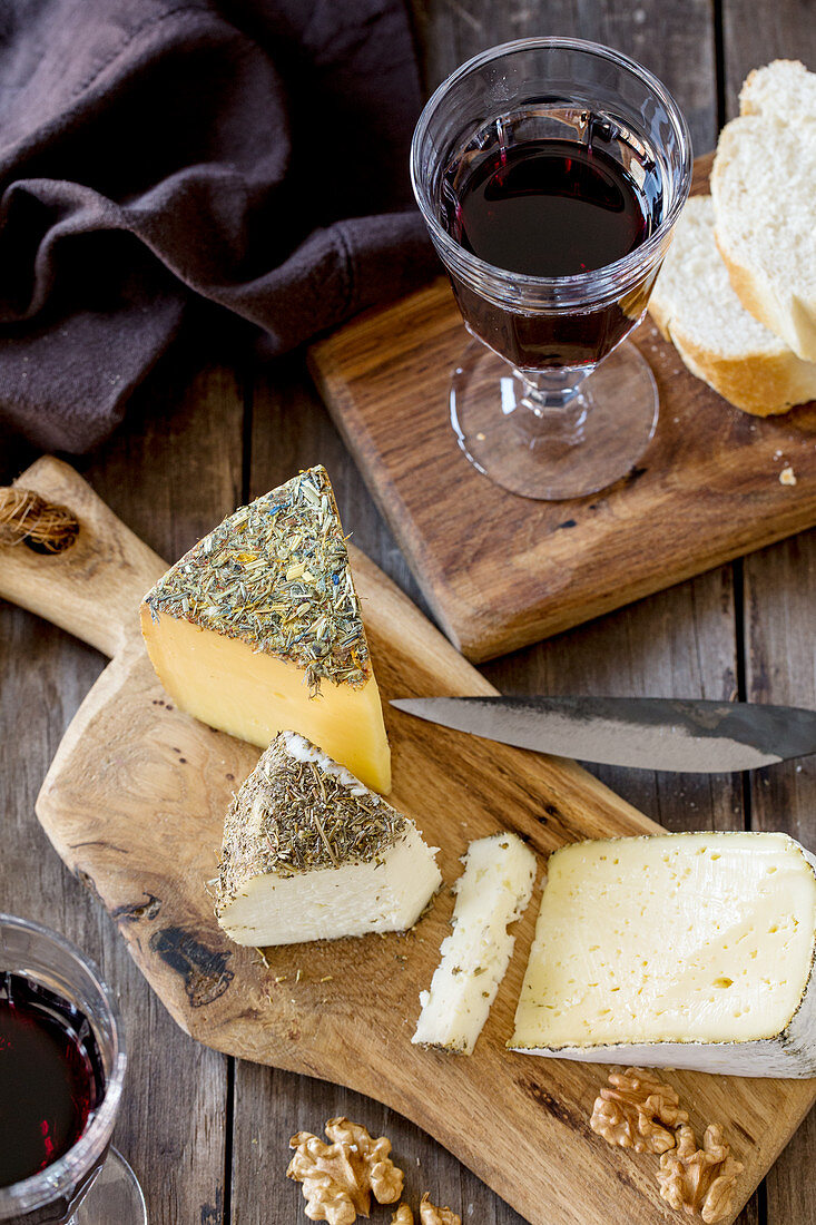 A cheese platter with bread, walnuts and red wine