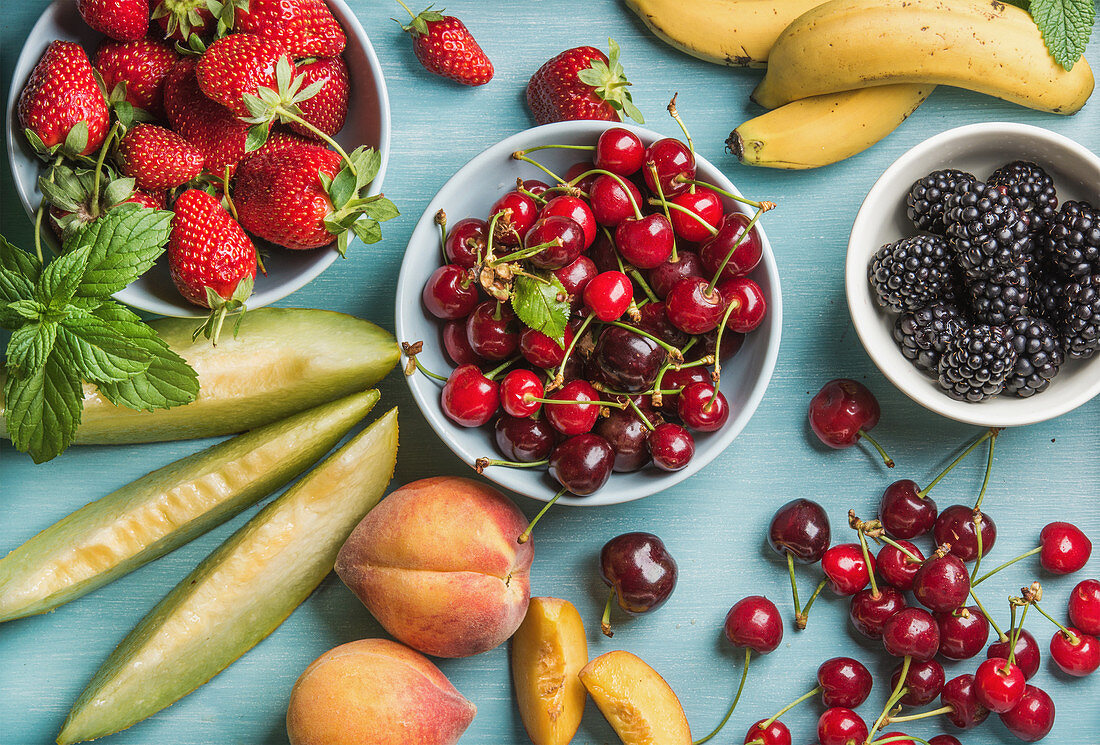 Gesunde Sommerfruchtsorten - Kirschen, Erdbeeren, Brombeeren, Pfirsiche, Bananen, Melonenscheiben und Minzblätter