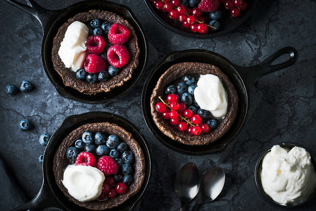 Chocolate Dutch babies with berries in cast-iron pans