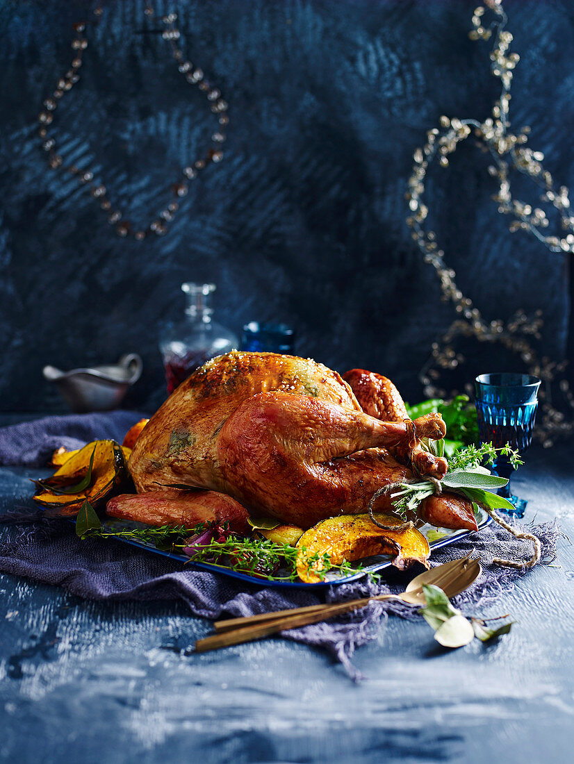 Whole roast turkey with pumpkin wedges and herbs