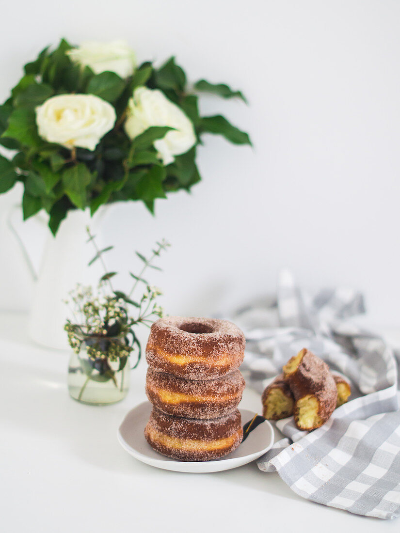 Doughnuts with cinnamon sugar, stacked on a plate and on a tea towel