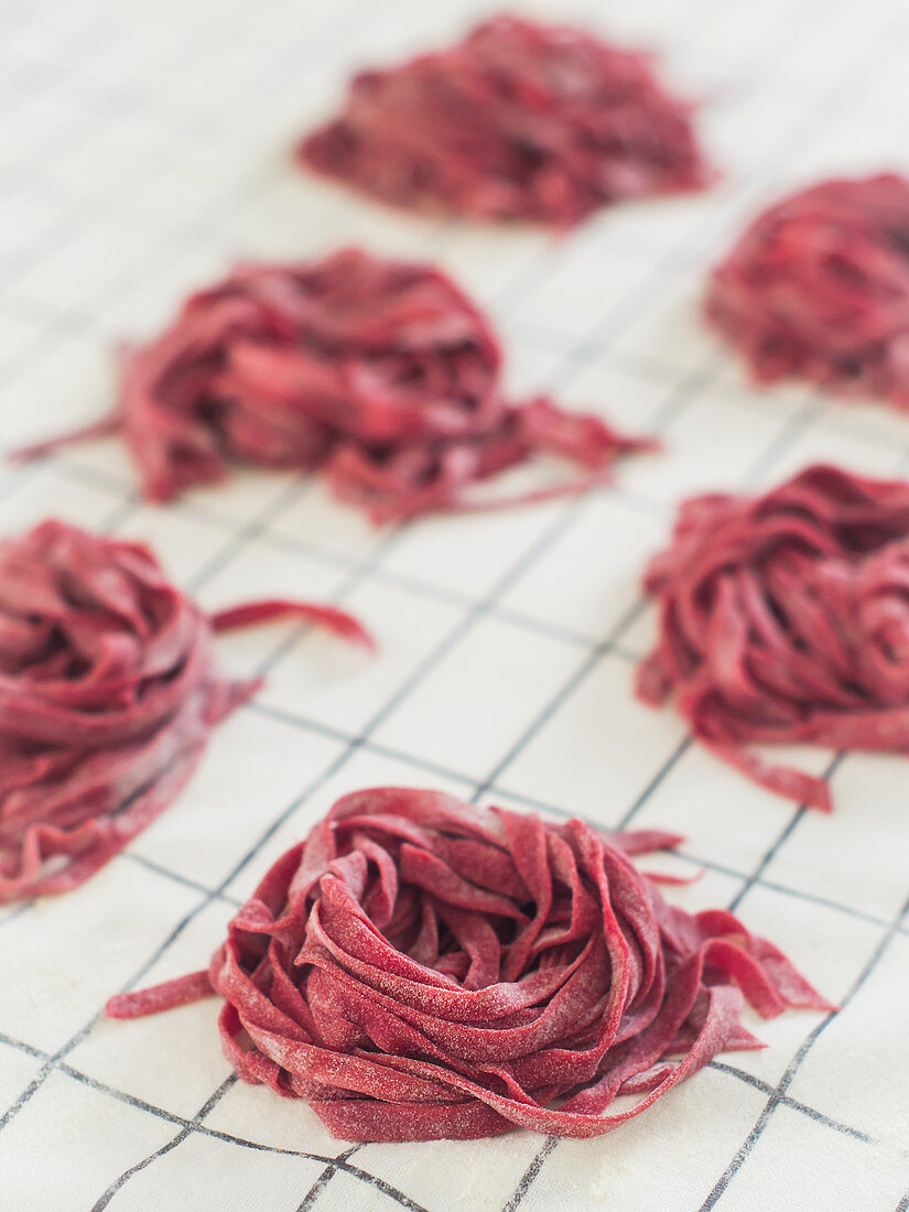 Homemade raw beetroot tagliatelle nests on a cloth