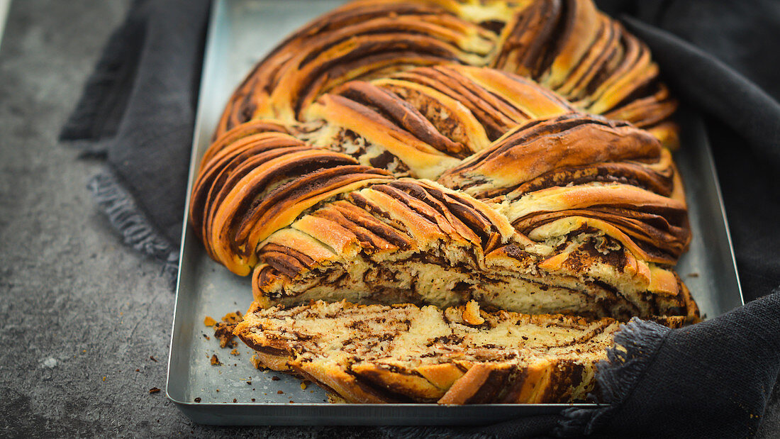 Plaited bread with chocolate and cinnamon, sliced on a baking tray
