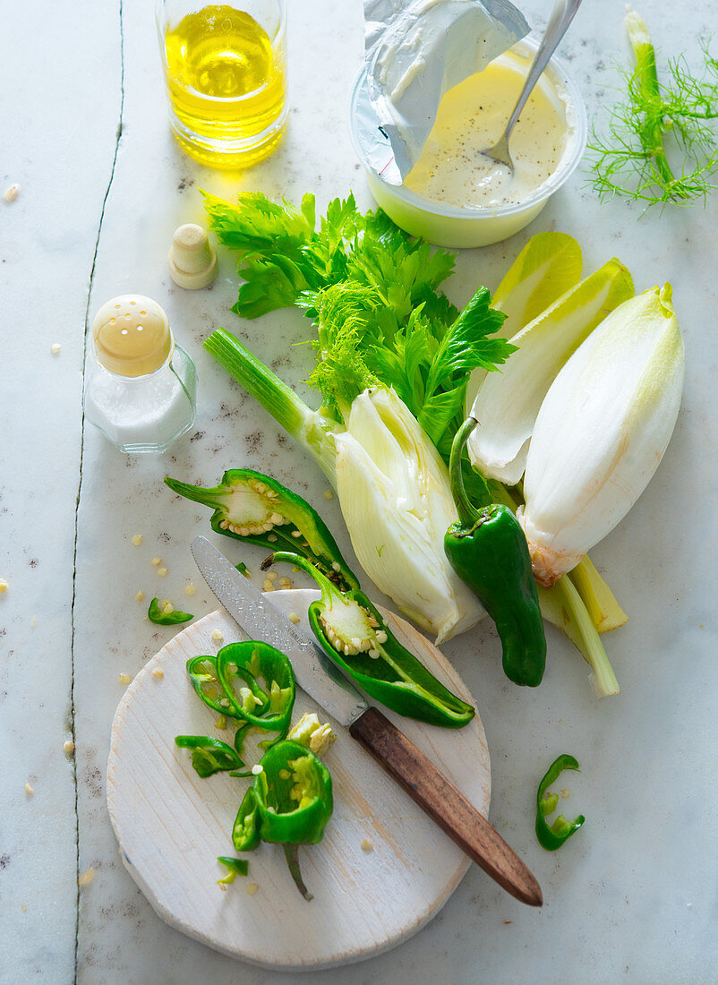 Zutatenstilleben mit Chicorée, Fenchel, Peperoni, Joghurt und Olivenöl