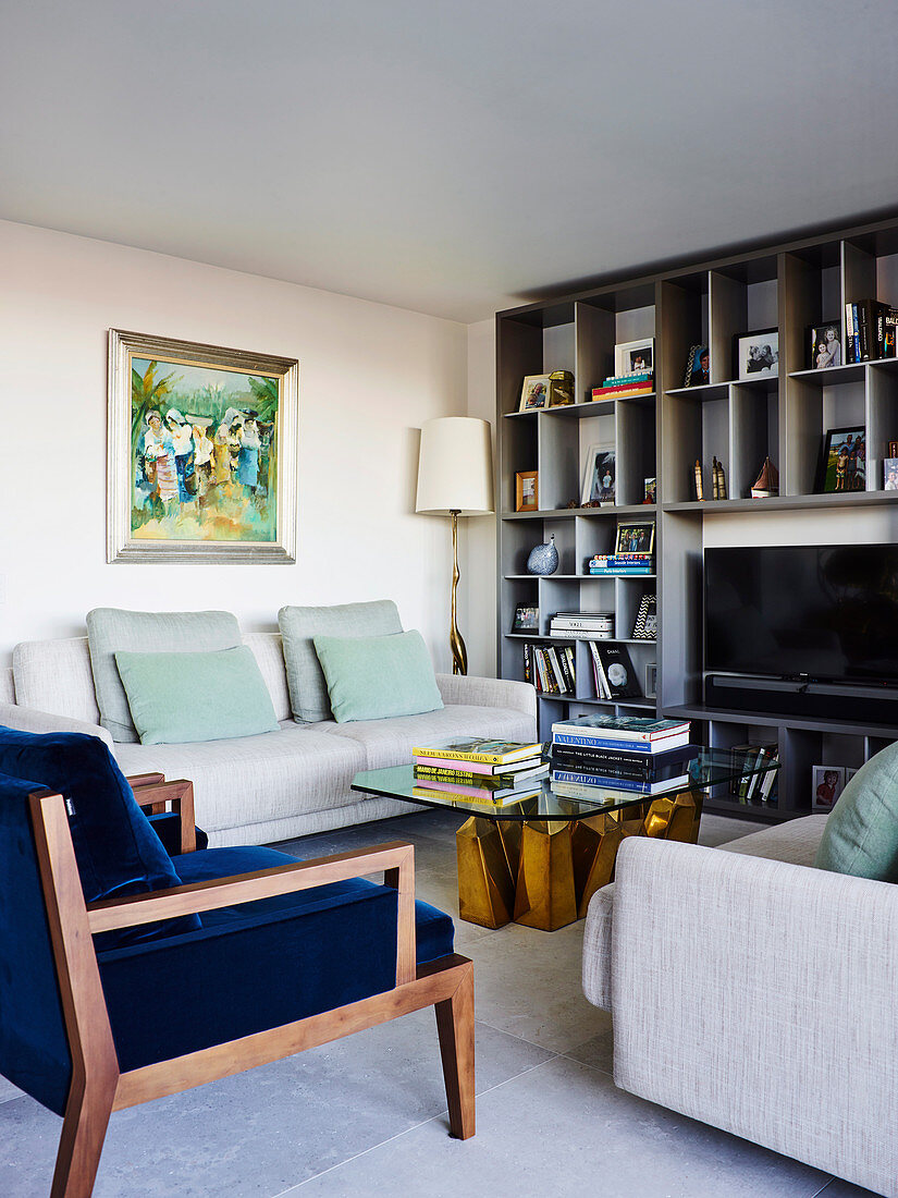 Light gray and dark blue upholstered furniture, glass coffee table and bookcase in the living room