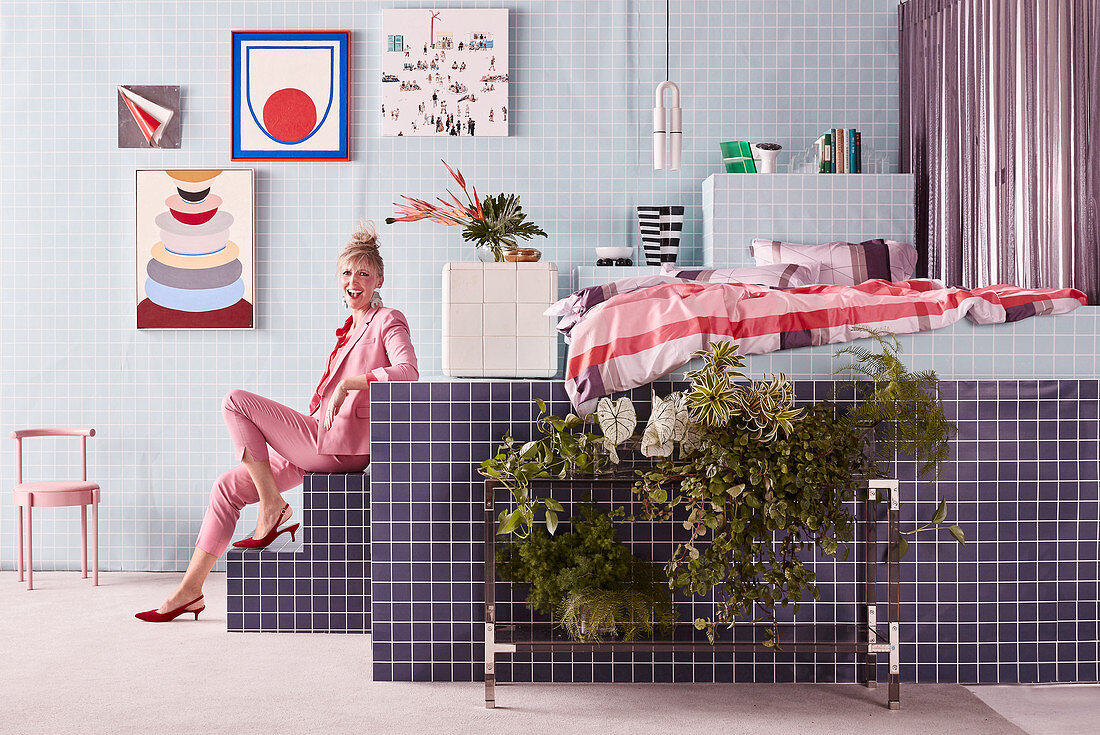 Woman sits on the steps to the tiled pedestal in the bedroom