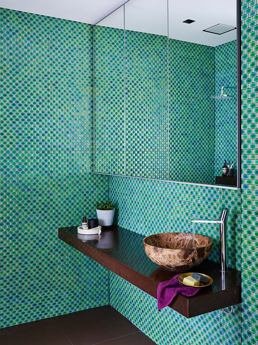 Spiegelschrank und Waschtisch im Bad mit Mosaikfliesen in Grüntönen