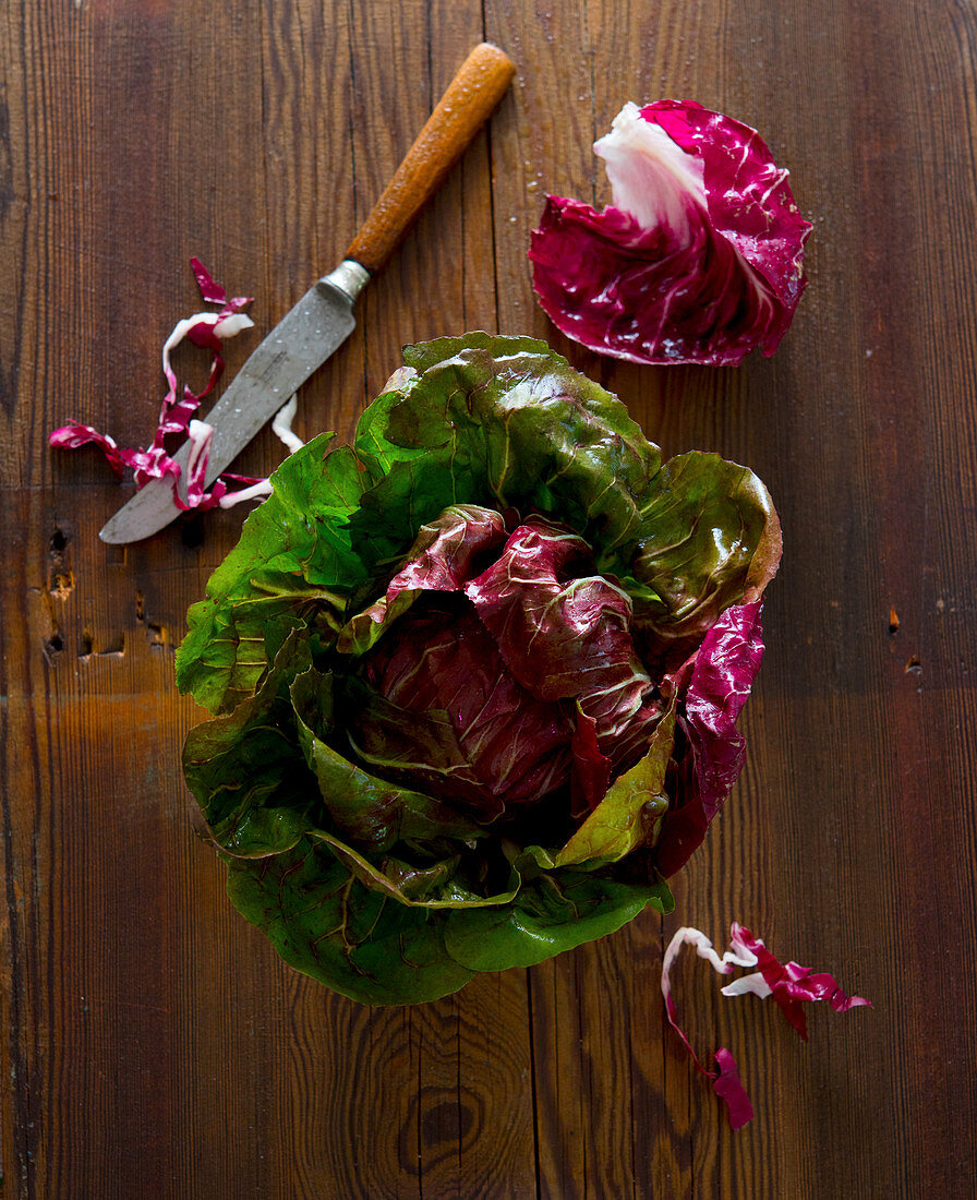 Fresh radicchio salad with a kitchen knife on a wooden surface