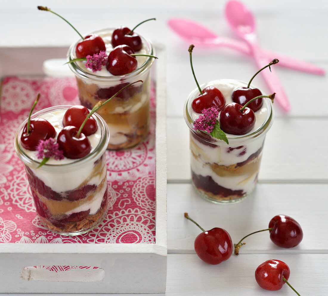 Vegan cherry and caramel dessert in glasses with caramel biscuits, almond yoghurt, caramel cream and cherry compote