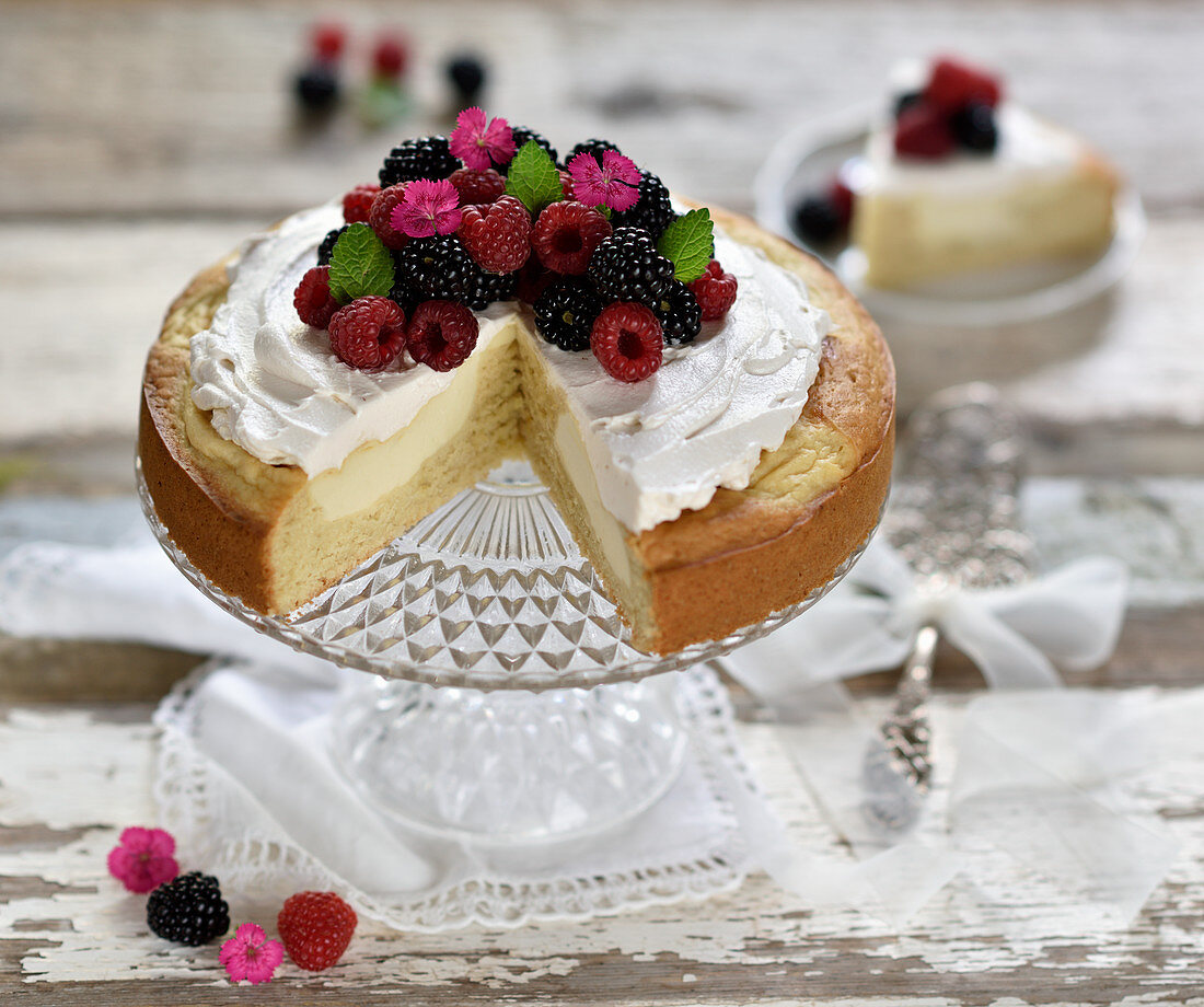 Veganer Zitronen-Cheesecake aus Rührteig und eingebackener Quarkschicht, dekoriert mit Sojasahne, Himbeeren und Brombeeren