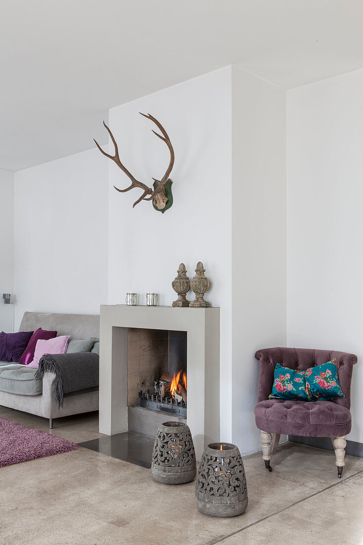 Lilac easy chair, fireplace and grey sofa in living room