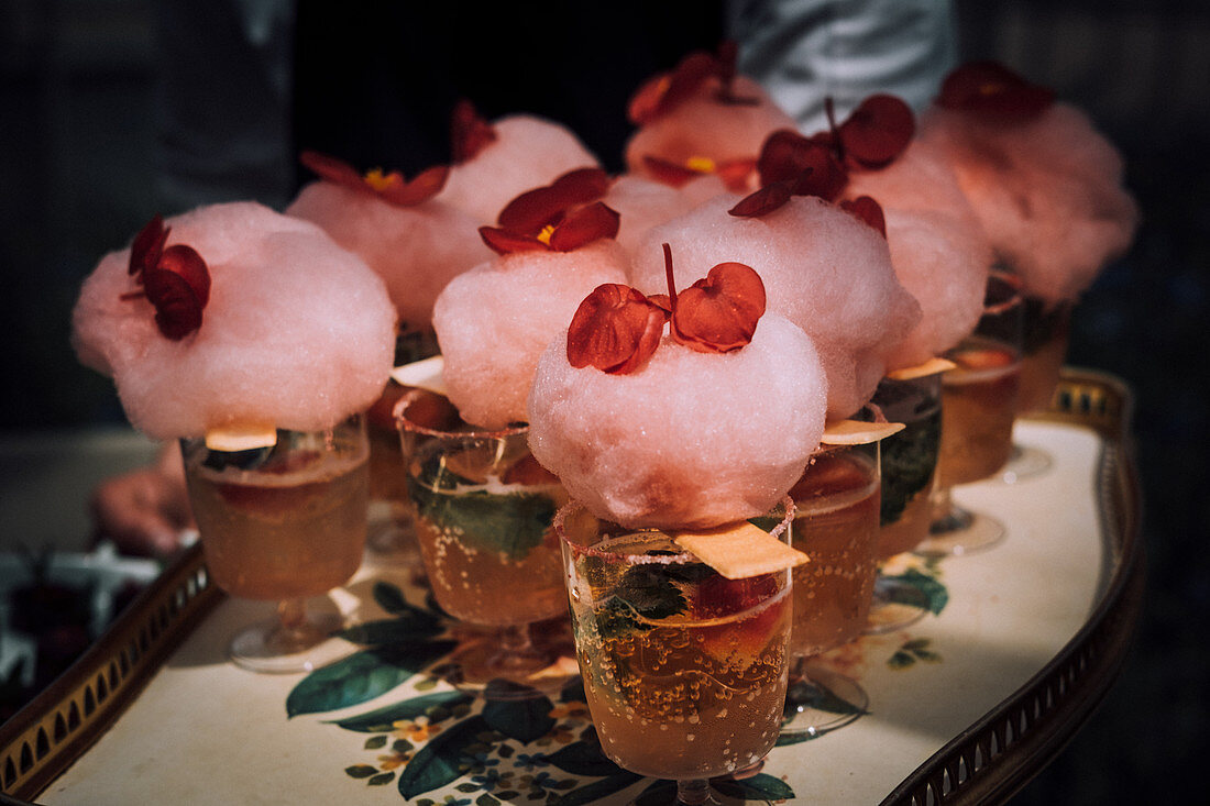Mit Zuckerwatte und Begonienblüten garnierte Cocktails