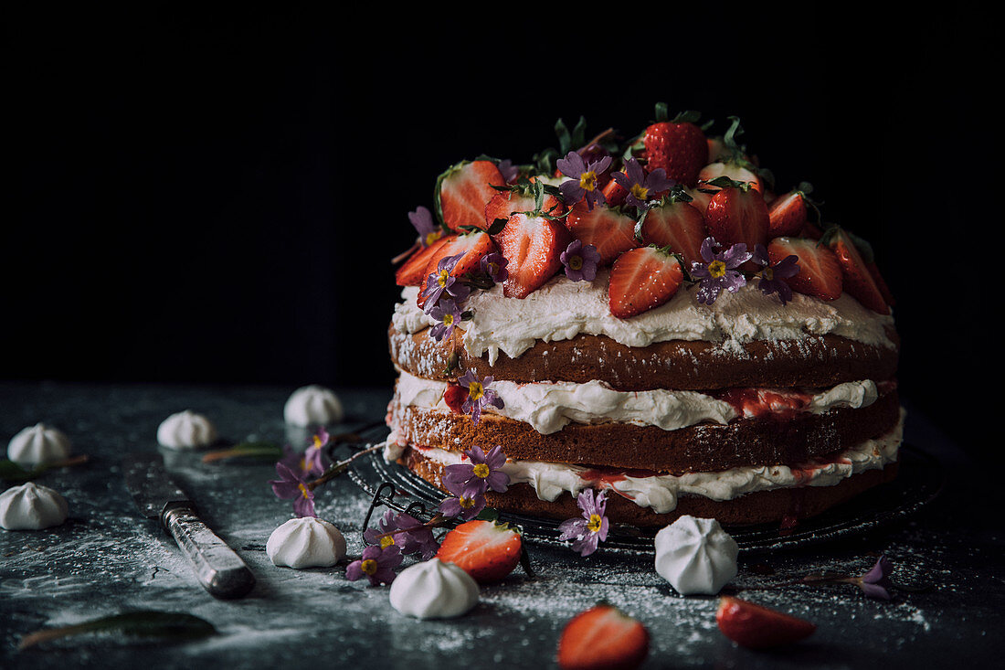 Dreischichtige Erdbeer-Sahnetorte mit Essblüten, Baisers und Erdbeersauce