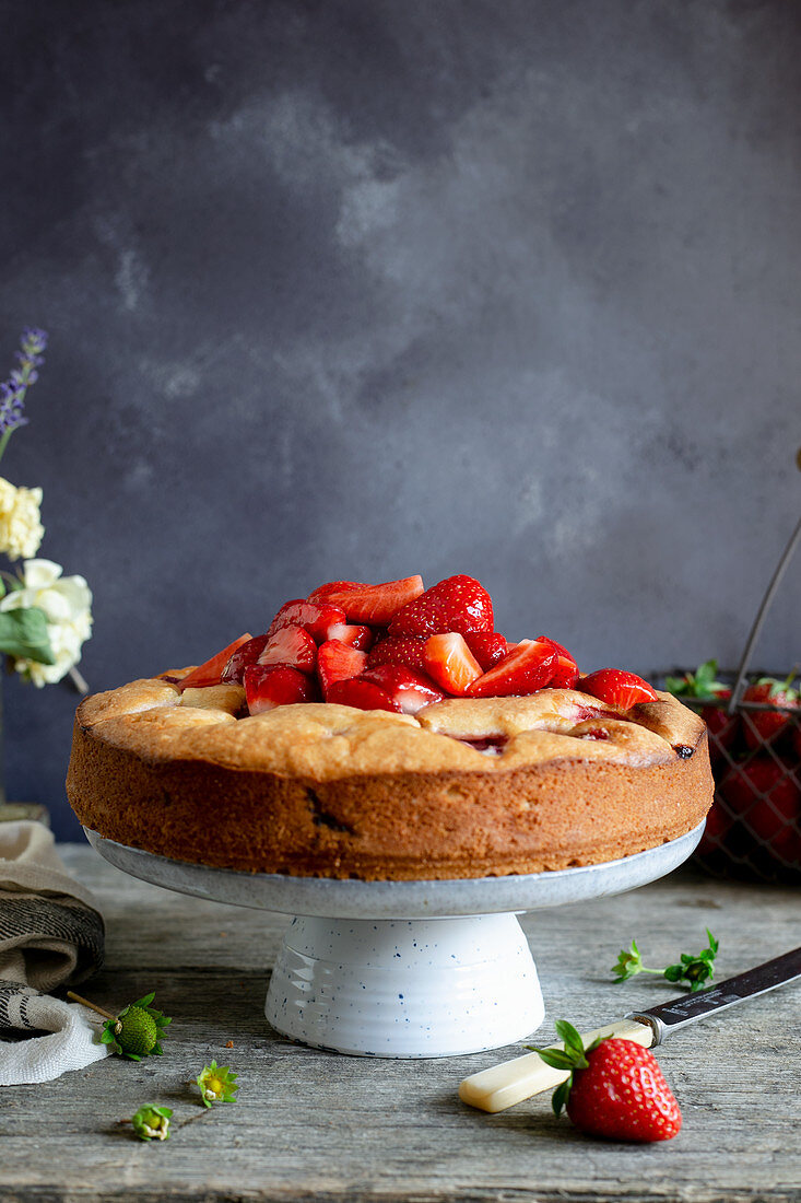 Strawberry cake on the cakestand, topped with fresh strawberries