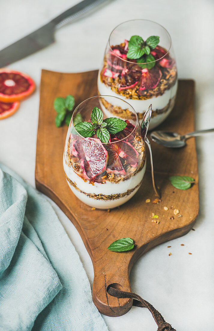 Greek yogurt, granola, blood orange layered parfait in glasses with mint leaves